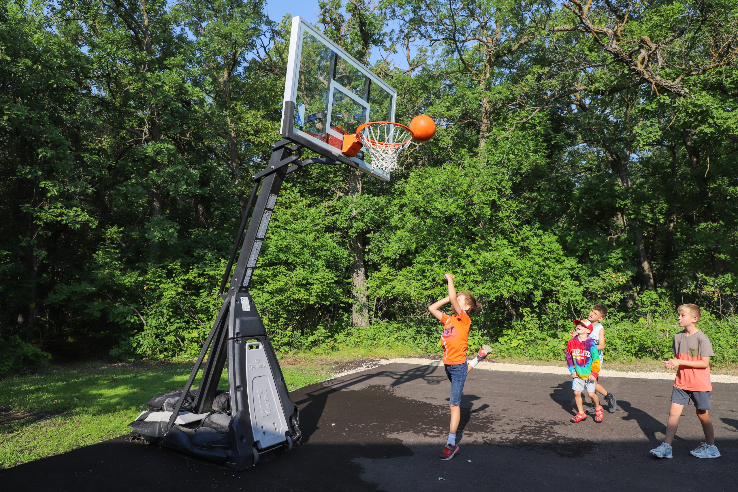 Three children on the basketball court, a basketball going into the hoop